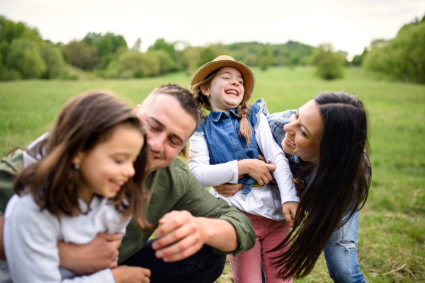 Front view of happy family with two small daughters having fun outdoors in spring nature.