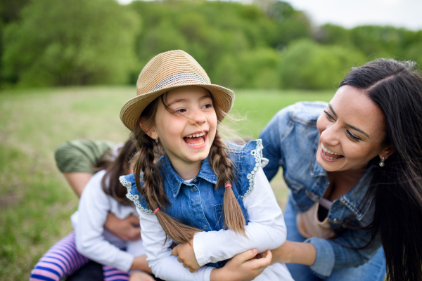 Happy family with two small daughters having fun outdoors in spring nature, playing.