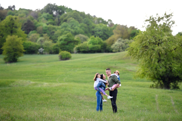 Happy family with two small daughters standing outdoors in spring nature, having fun.