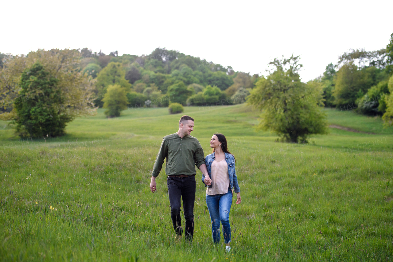 Happy couple in love walking outdoors in spring nature, holding hands.