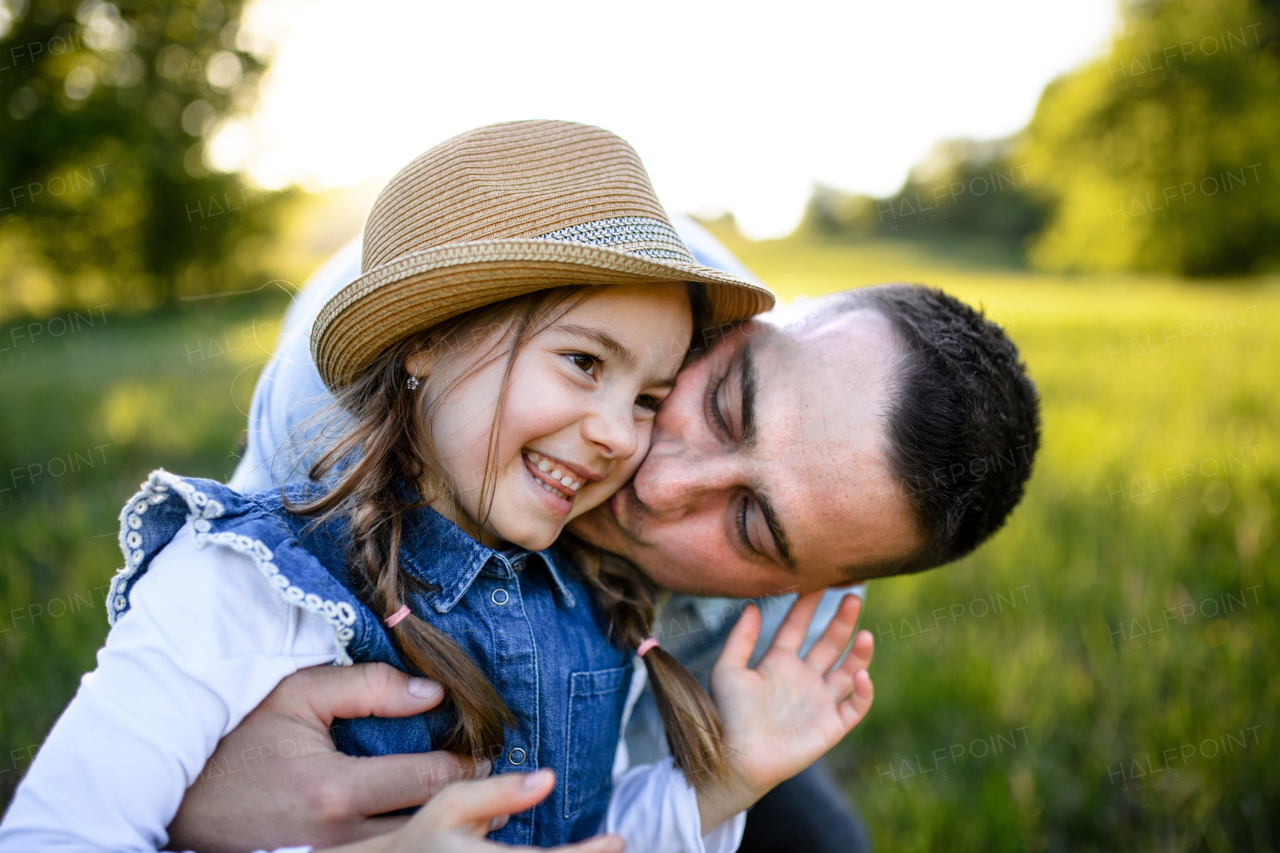 Front view of father playing with small daughter outdoors in spring nature, having fun.