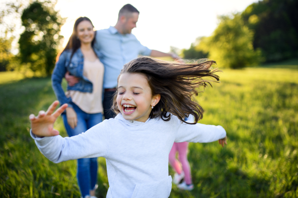 Happy family with two small daughters having fun outdoors in spring nature, running.