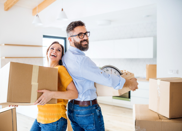 A young happy couple furnishing new house, having fun. A moving in new home concept.