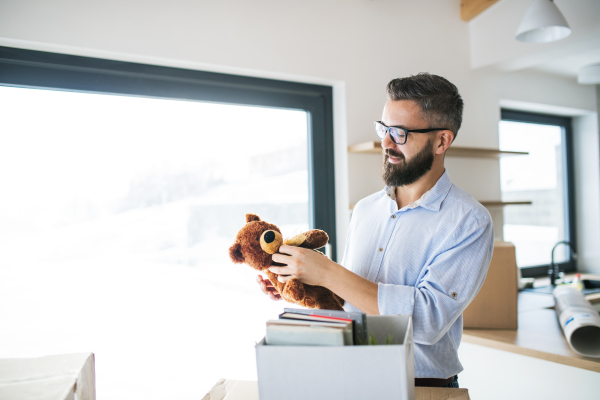 A mature man with a teddy bear furnishing new house, a moving in new home concept.