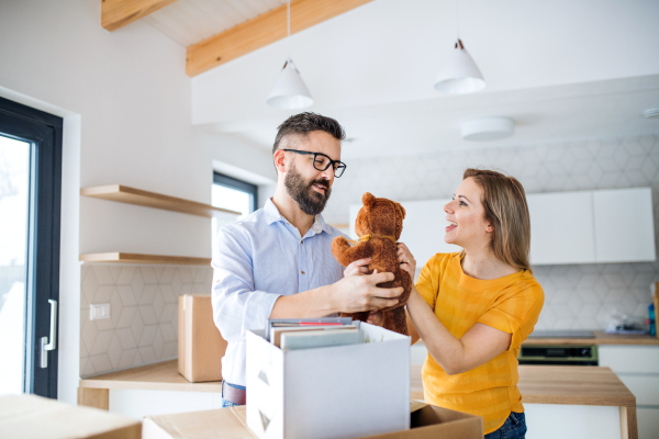 A young happy couple furnishing new house, having fun. A moving in new home concept.