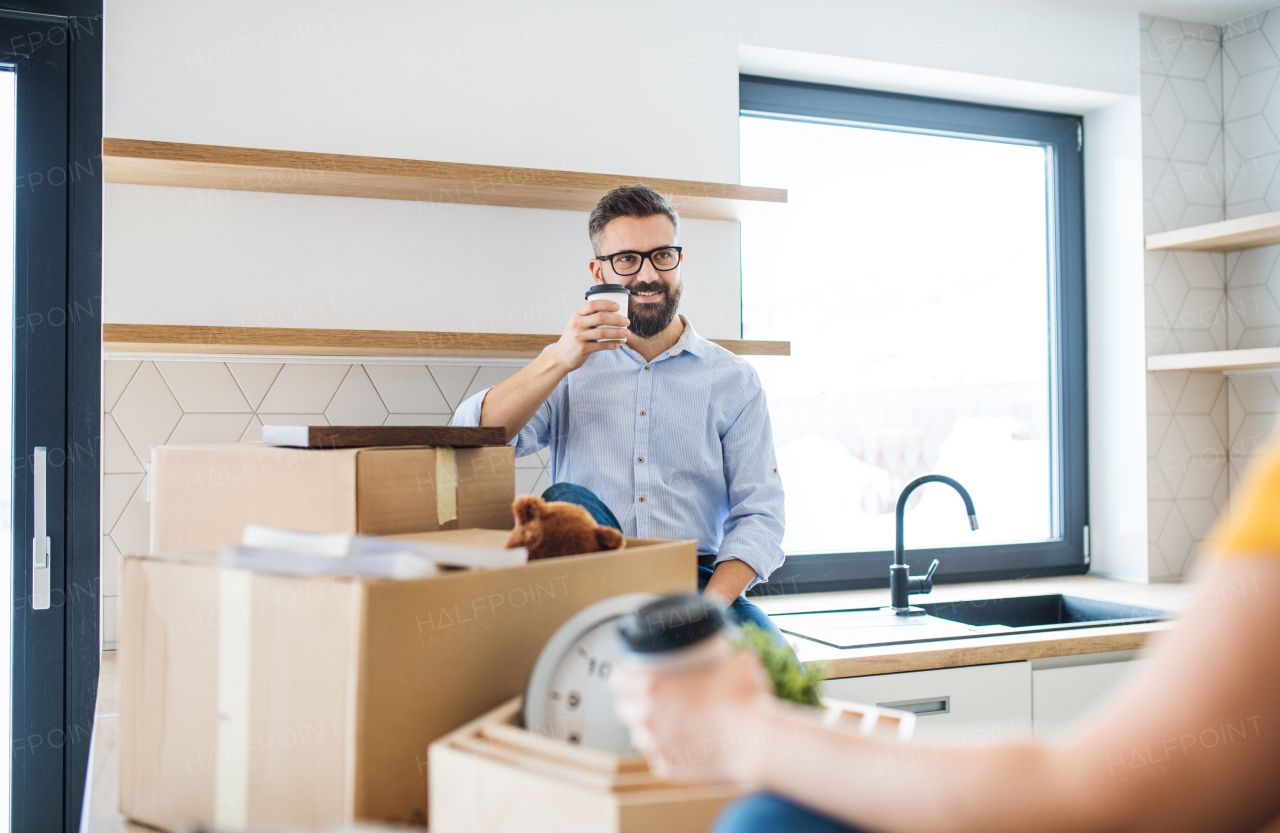 A young happy couple drinking coffee when furnishing new house, a moving in new home concept.