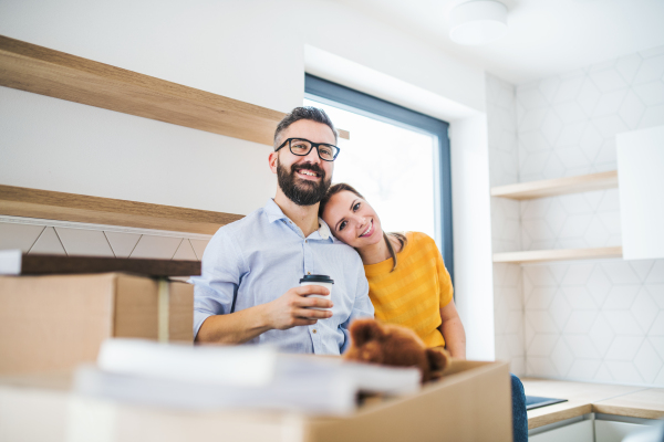 A young happy couple drinking coffee when furnishing new house, a moving in new home concept.