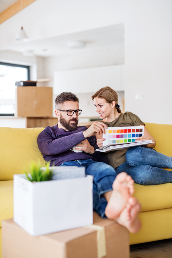 A young couple with color samples sitting on sofa, moving in new home and talking.