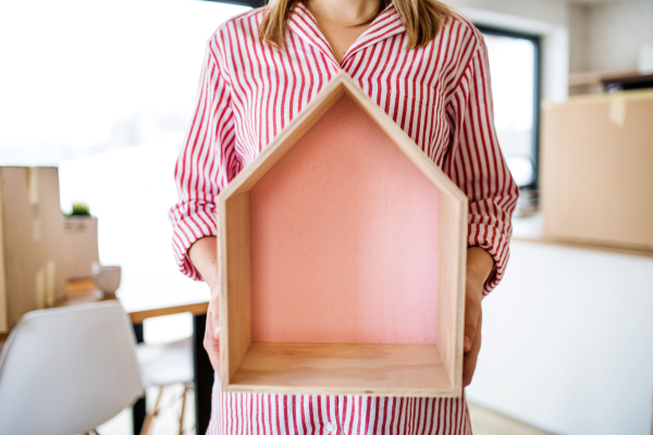 A midsection of woman with wooden house moving in new home, a concept. Copy space.