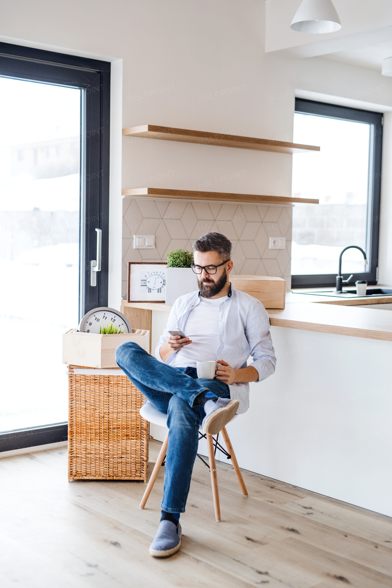 A mature man with coffee and smartphone moving in new home, text messaging.