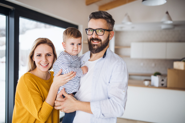 A portrait of happy young family with a toddler girl moving in new home.