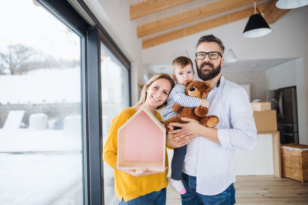 A portrait of happy young family with a toddler girl moving in new home.