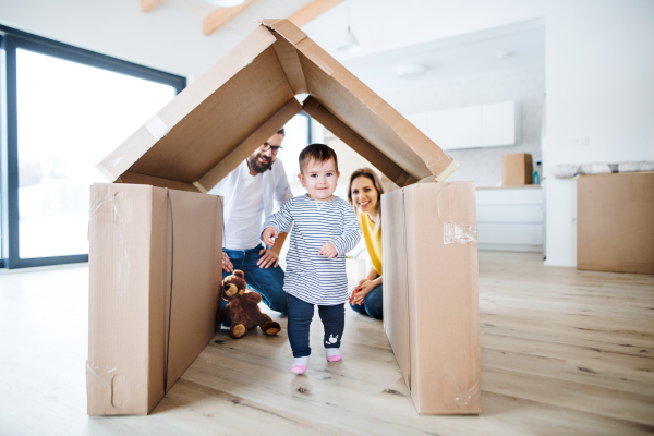 A portrait of happy young family with a toddler girl moving in new home.