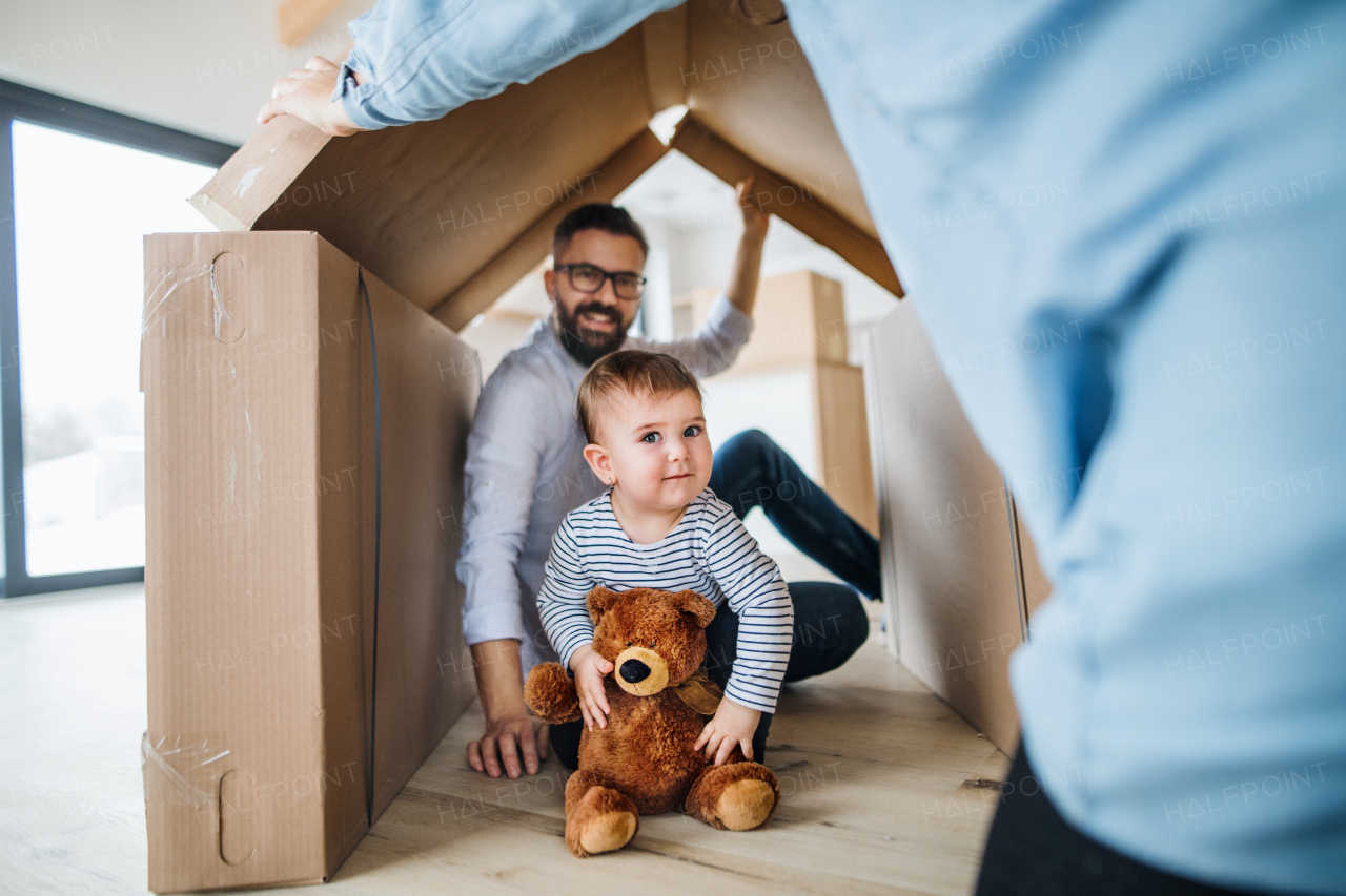 A portrait of happy young family with a toddler girl, moving in new home concept.