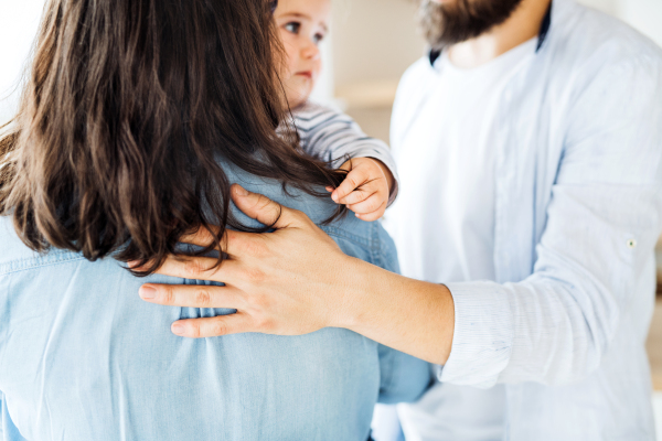 A midsection of young family with toddler girl standing indoors at home.