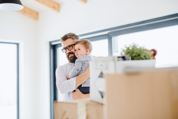 A portrait of happy young father holding a toddler girl, moving in new home.