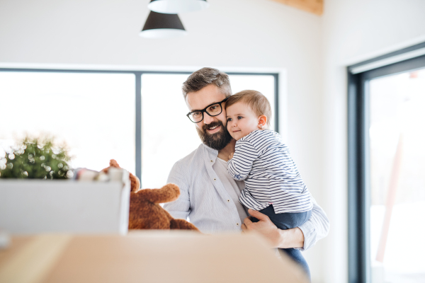 A portrait of happy young father holding a toddler girl, moving in new home.