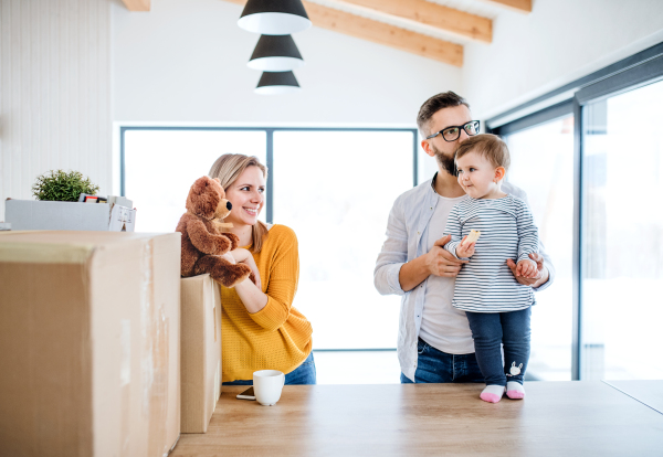 A portrait of happy young family with a toddler girl moving in new home.