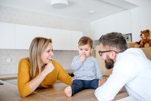 A portrait of happy young family with a toddler girl moving in new home.