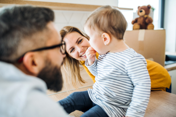 A portrait of happy young family with a toddler girl moving in new home.