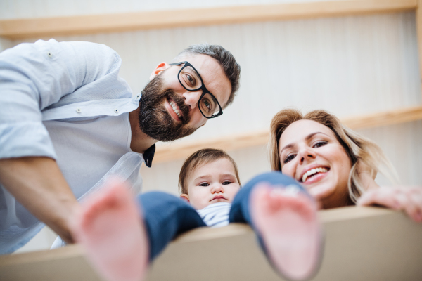 A low-angle view of happy young family with a toddler girl moving in new home.