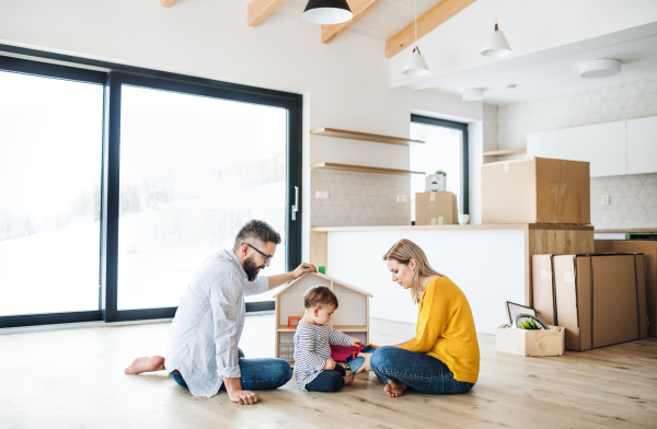 A portrait of happy young family with a toddler girl moving in new home, playing.