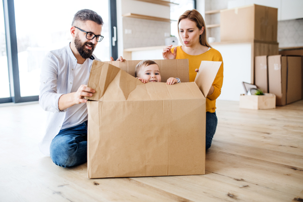 A portrait of happy young family with a toddler girl moving in new home.