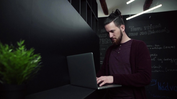 A young businessman with laptop in office, working. Slow motion.