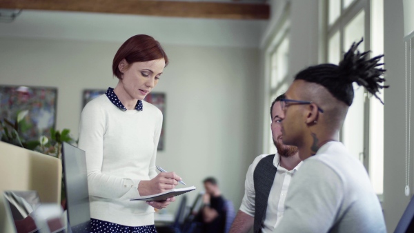 A group of young businesspeople talking in office, start-up concept.