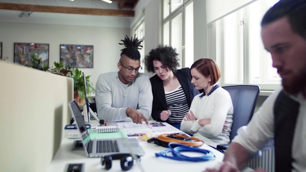 A group of young businesspeople talking in office, start-up concept.