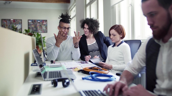 A group of young businesspeople talking in office, start-up concept.