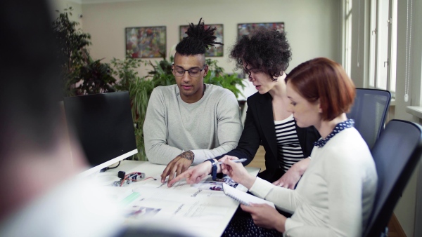 A group of young businesspeople talking in office, start-up concept.