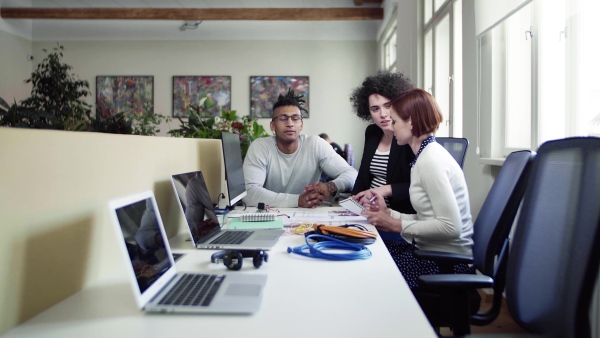 A group of young businesspeople talking in office, start-up concept.