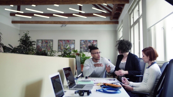 A group of young businesspeople talking in office, start-up concept.