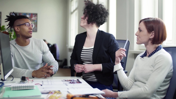 A group of young businesspeople talking in office, start-up concept.