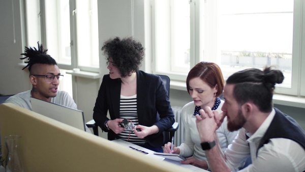 A group of young businesspeople talking in office, start-up concept.