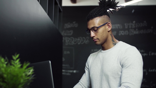 A young businessman with laptop in office, working.