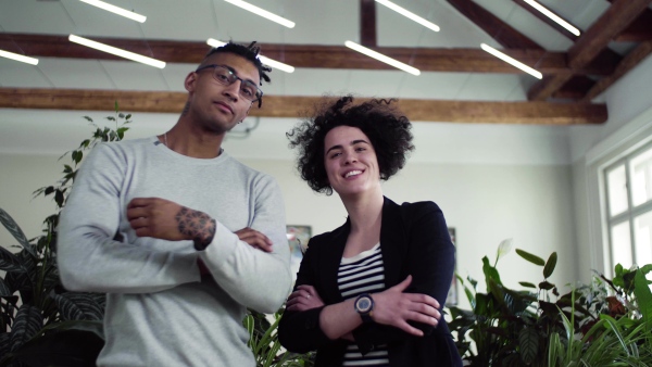 A portrait of young businesspeople standing in office, looking at camera.