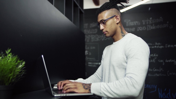 A young businessman with laptop in office, working.