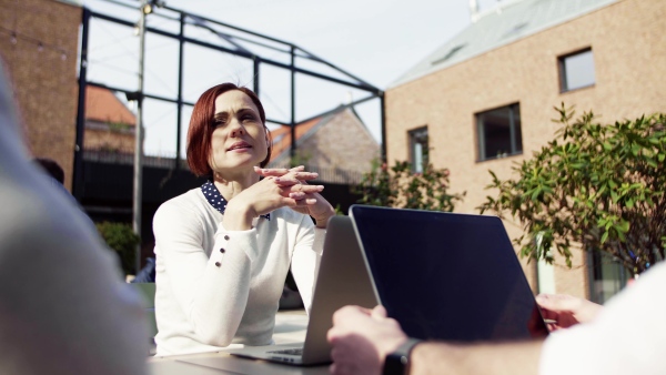 A group of young businesspeople using laptop in courtyard, start-up concept.