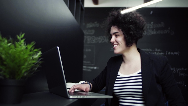 A young businesswoman with laptop in office, working.