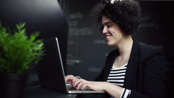 A young businesswoman with laptop in office, working. Slow motion.