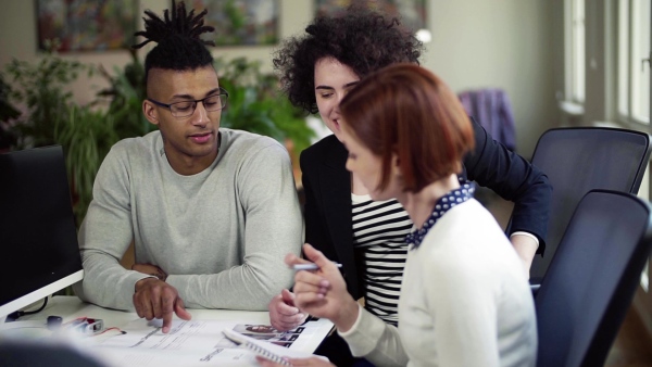 A group of young businesspeople talking in office, start-up concept. Slow motion.