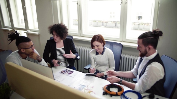 A group of young businesspeople talking in office, start-up concept. Slow motion.