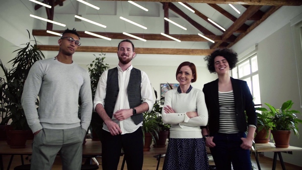 Portrait of group of young businesspeople standing in office, looking at camera. Slow motion.