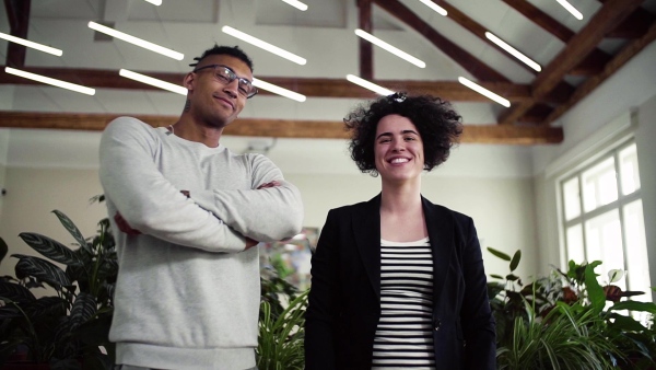 A portrait of young businesspeople standing in office, looking at camera. Slow motion.