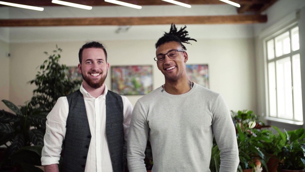 A portrait of young businesspeople standing in office, looking at camera. Slow motion.