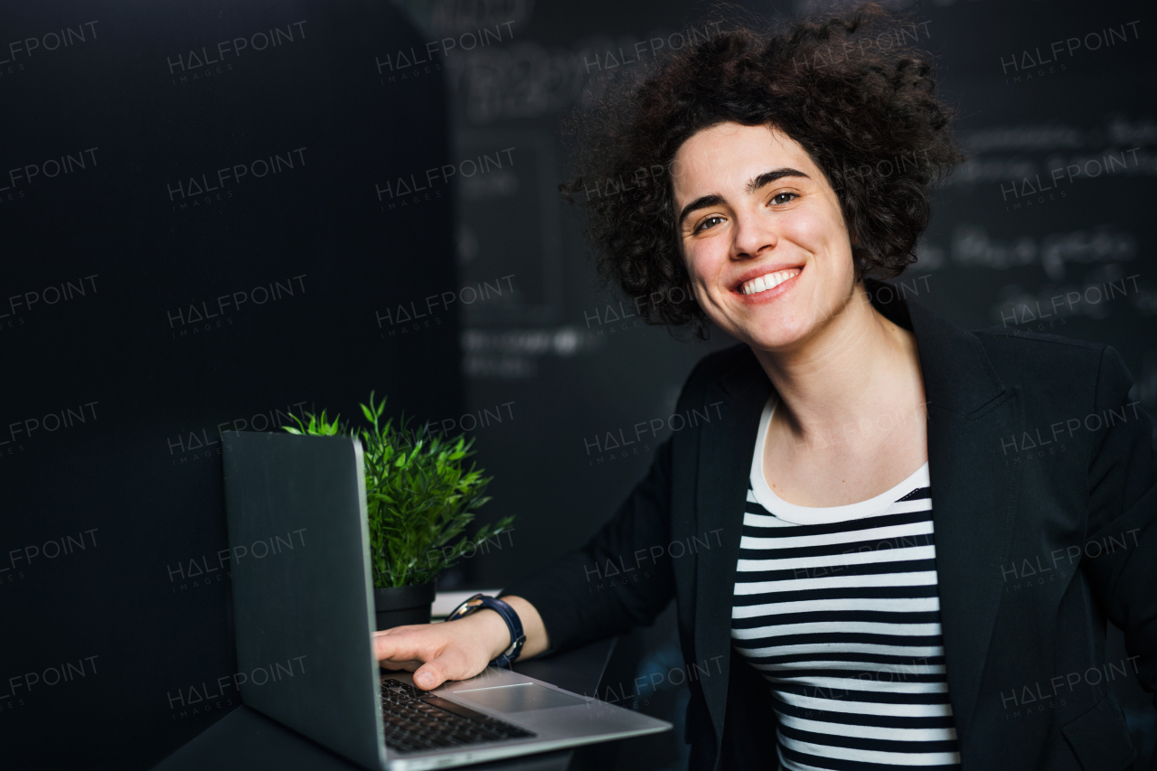 A young businesswoman with laptop in office, working.