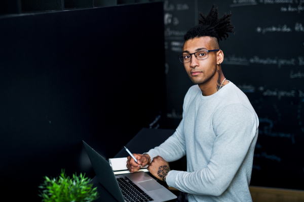 A young businessman with laptop in office, working.