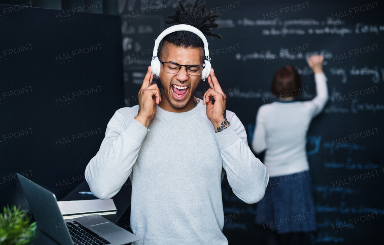 A young businessman with headphones in office, listening to music and singing.